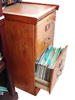 Photo of a wooden file cabinet with an open drawer and visible file folders