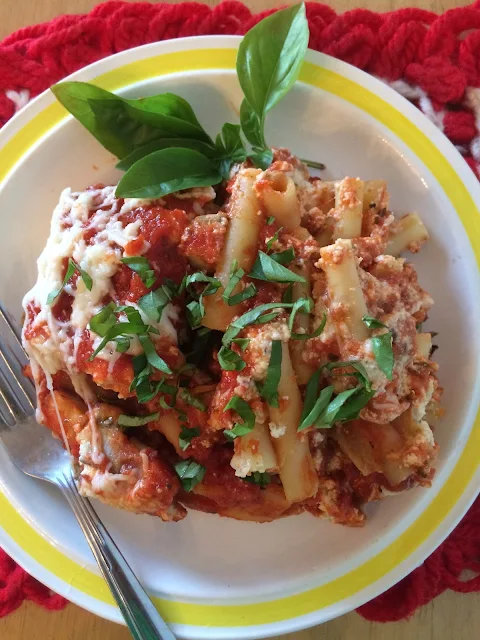 Finished photo of a serving of eggplant baked ziti topped with fresh basil.