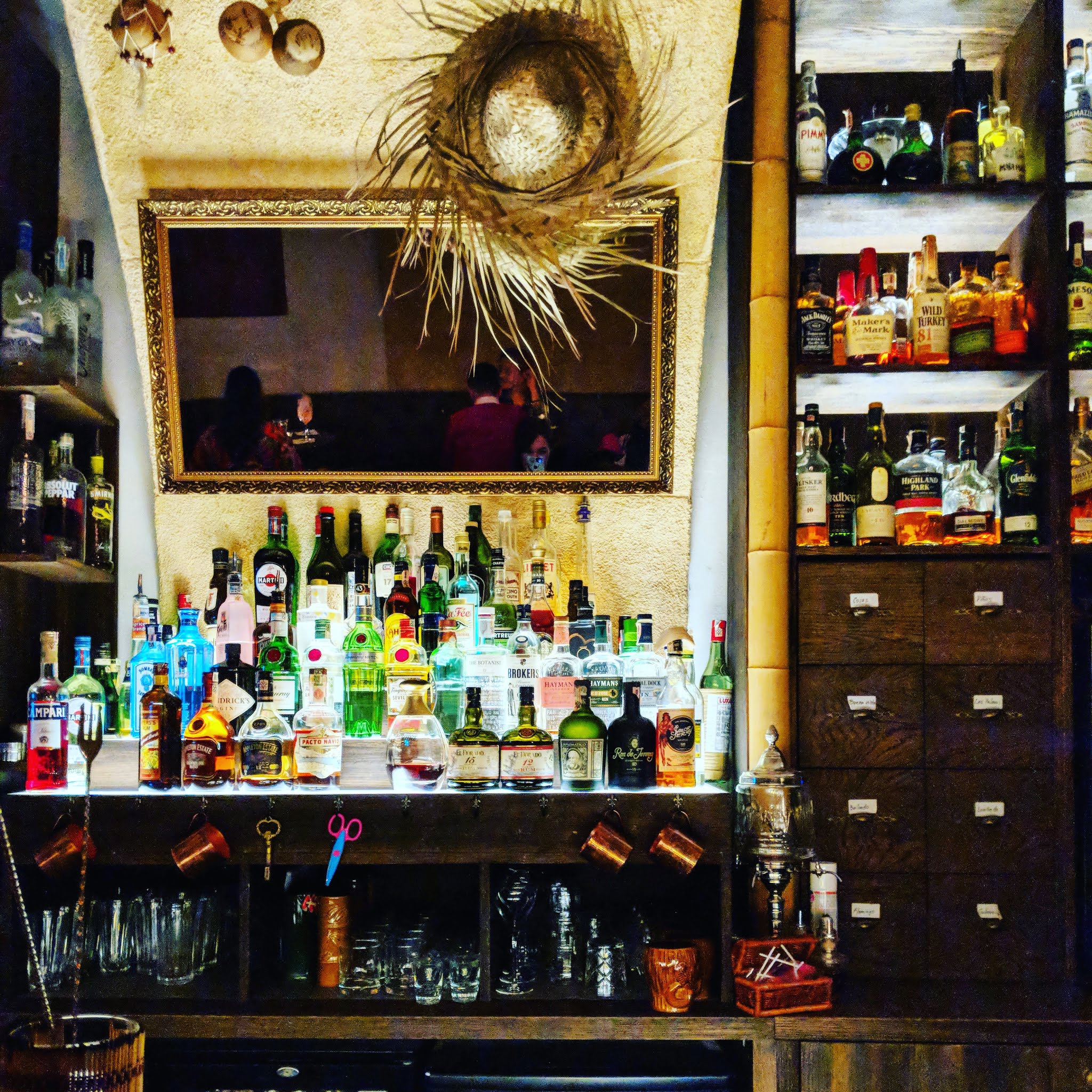 dimly lit bar with mirror straw hat and bottles of alcohol