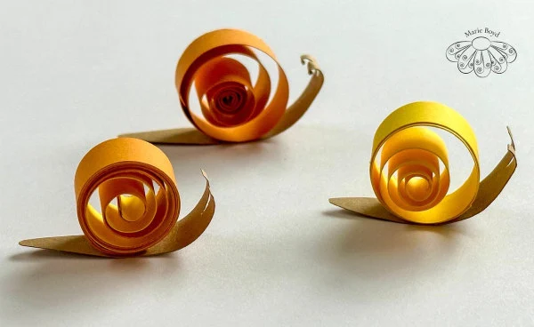 three yellow snails made of coiled paper strips