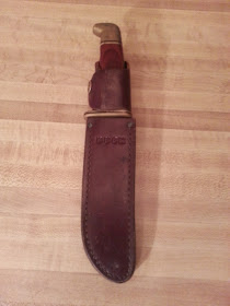 Buck 119 in leather sheath. Front view.