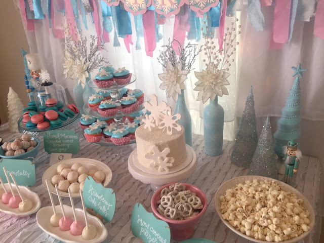 Winter ONEderland 1st birthday party decoration ideas. Food table backdrop and decorations. Hot chocolate and coffee bar chalkboard sign. Winter ONEderland hot chocolate party favors. First birthday outfit. Snowflake smash cake. French macarons. Happy Birthday banner