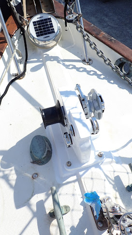 A shiny white windlass is bolted to a rather dirty looking foredeck