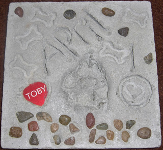 A picture of Toby's paw print stone. It says April 10 (2010). And has Toby's name spelled out in rocks