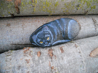 Piedra pintada con un gato negro.