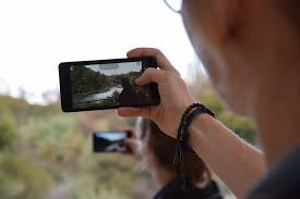 A boy taking photo on Phone with only one hand.