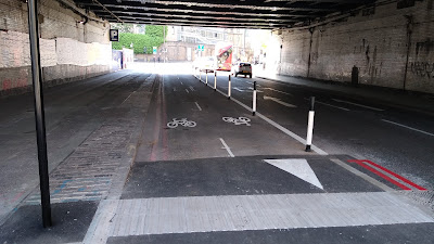 A piece of road with the protected two-way cycle lane back at road level in a tunnel.