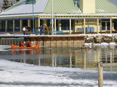 Bright orange inflatable boat launched by Mississauga Fire Dept at Credit River in front of Snug Harbour restaurant.