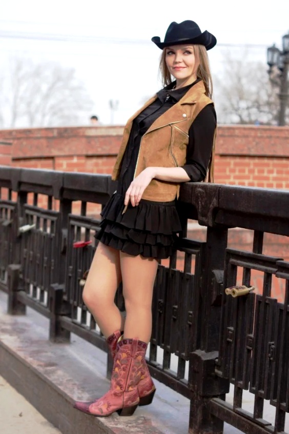 Woman wearing black mini dress and brown cowboy boots