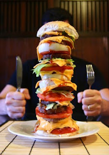 giant burger with person behind it ready to eat