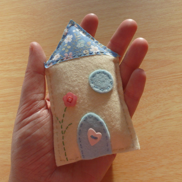 Miniature felt house hand sewn and held in hand