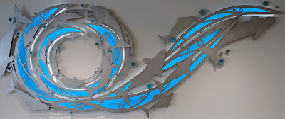 A dolphin wall sculpture in aluminum and blue acrylic.