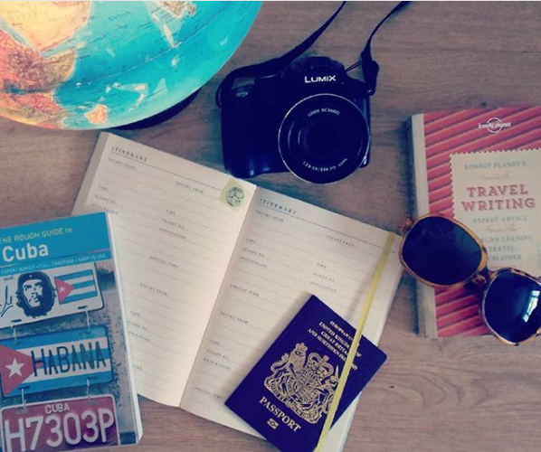 Travel planning, including globe, notebook, passport and Cuba travel guide