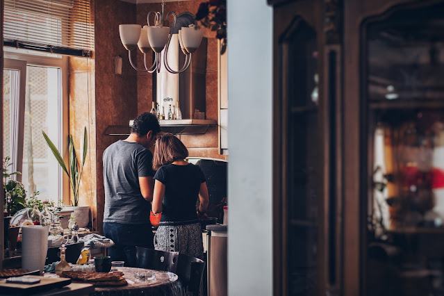 A husband and a wife helping each other in the kitchen.
