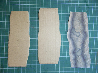 Two shapes cut out of cardboard, with the corrugations at right angles and floor plan cut out from printed page,
