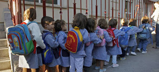 Niños haciendo la fila en la puerta de un colegio. 