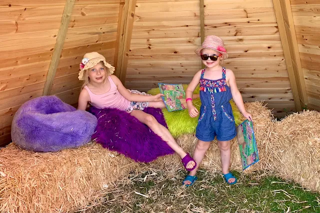 Inside a wooden teepee with haybales to sit on