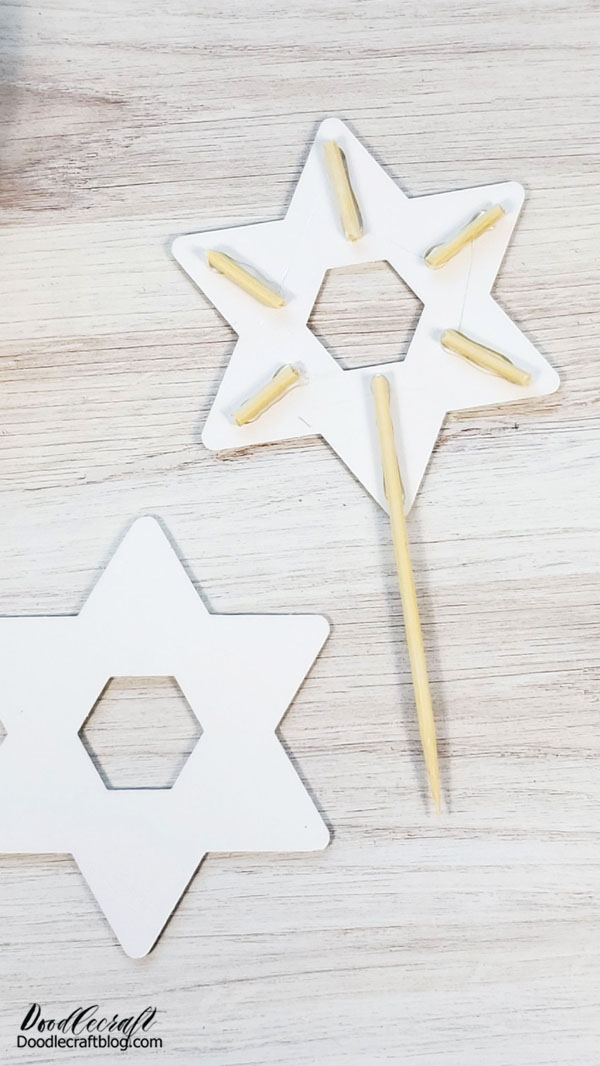 Use the hot glue gun to glue the star layers together.   Then cut a dowel into small pieces and glue them around the peaks of the star, as well as a stick coming out of the base to insert into cake.    Then hot glue the second star on the backside, so the cake topper looks amazing from any angle.