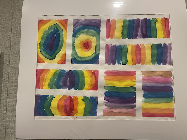 This piece too was done by an elementary student. It is various different rectangles displayed in a 3x3 grid with different shapes and drawings using the colors of the rainbow.