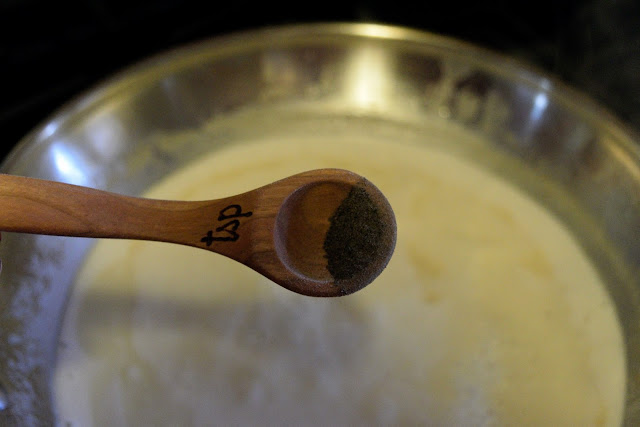 A picture of a measuring spoon over a bowl with black pepper in it. 