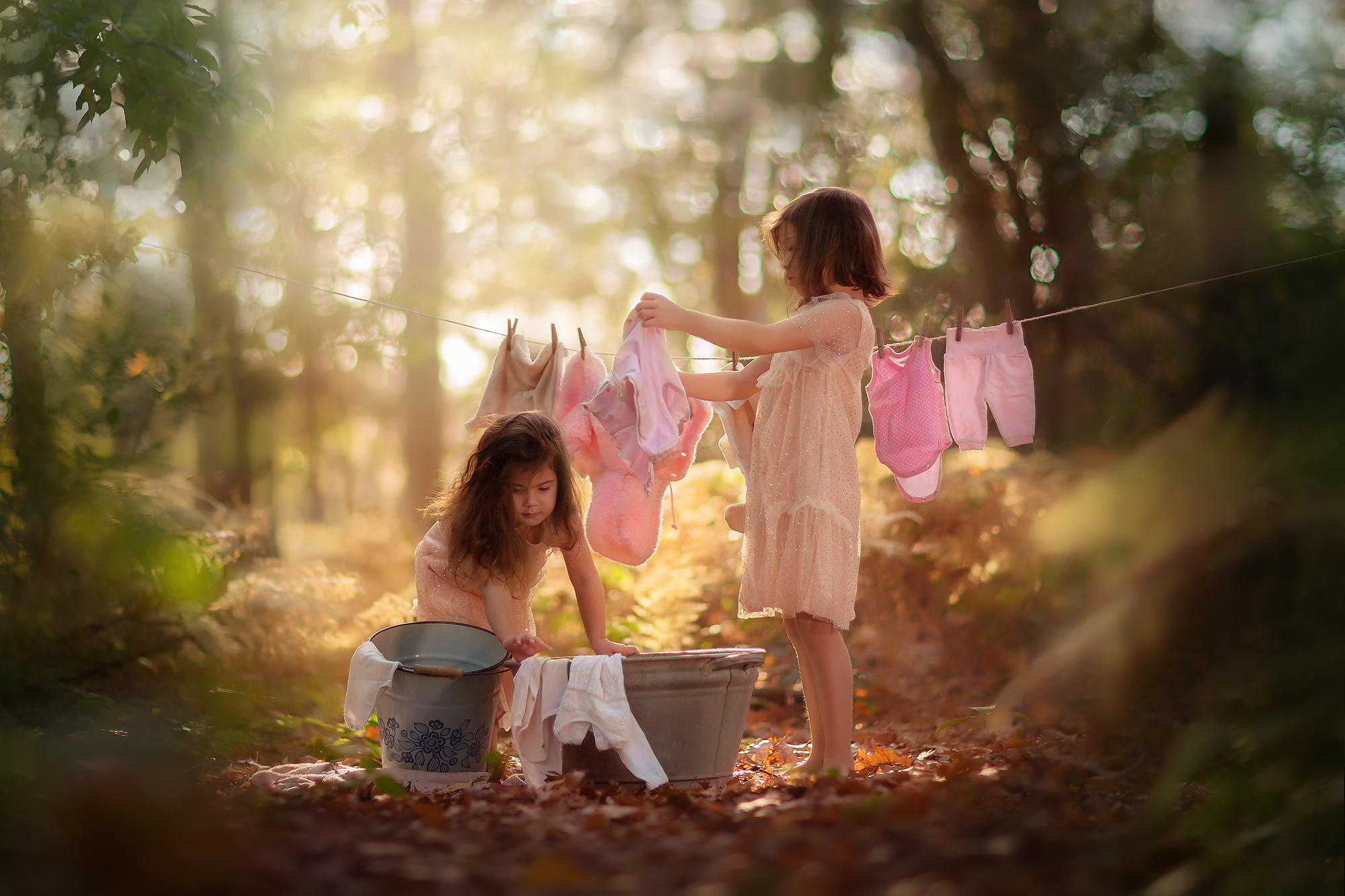 fine art portret van twee zusjes die de was ophangen in het bos door natuurlijk licht kinderfotograaf Willie Kers uit Apeldoorn