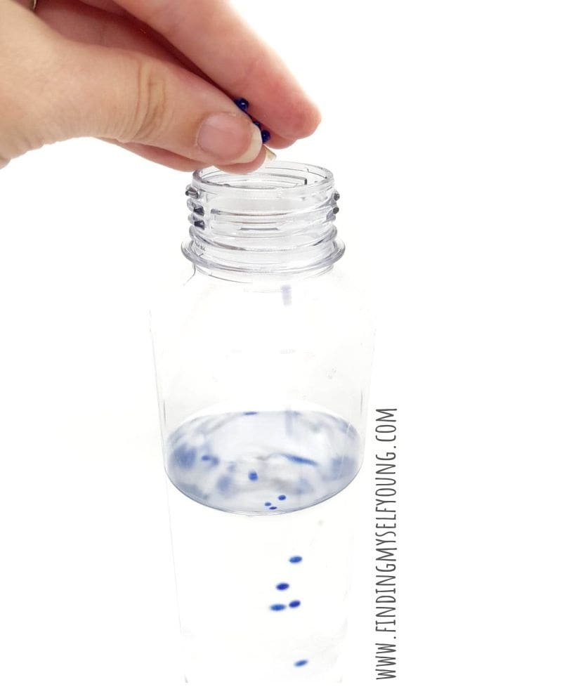 adding blue water beads to summer sensory bottle