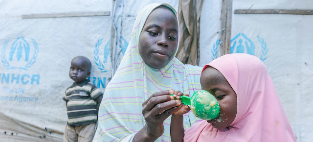 Una madre alimentando a sus hijos con cereales que ha recibido en un punto de distribución del Programa Mundial de Alimentos en Maiduguri, NigeriaPMA/Oluwaseun Oluwamuyiwa