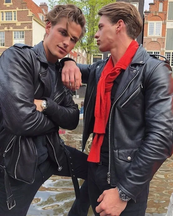 Twins standing outside in a city wearing black leather biker jackets