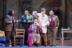 IN REVIEW: (from left to right) bass-baritone DONALD HARTMANN as Colline, tenor ARNOLD LIVINGSTON GEIS as Rodolfo, baritone ROBERT WELLS as Benoît, baritone DAVID PERSHALL as Marcello, and baritone SIDNEY OUTLAW as Schaunard in Greensboro Opera's November 2022 production of Giacomo Puccini's LA BOHÈME [Photograph by VanderVeen Photographers, © by Greensboro Opera]