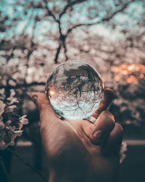 hand holding a mirror ball showing reflection of the world