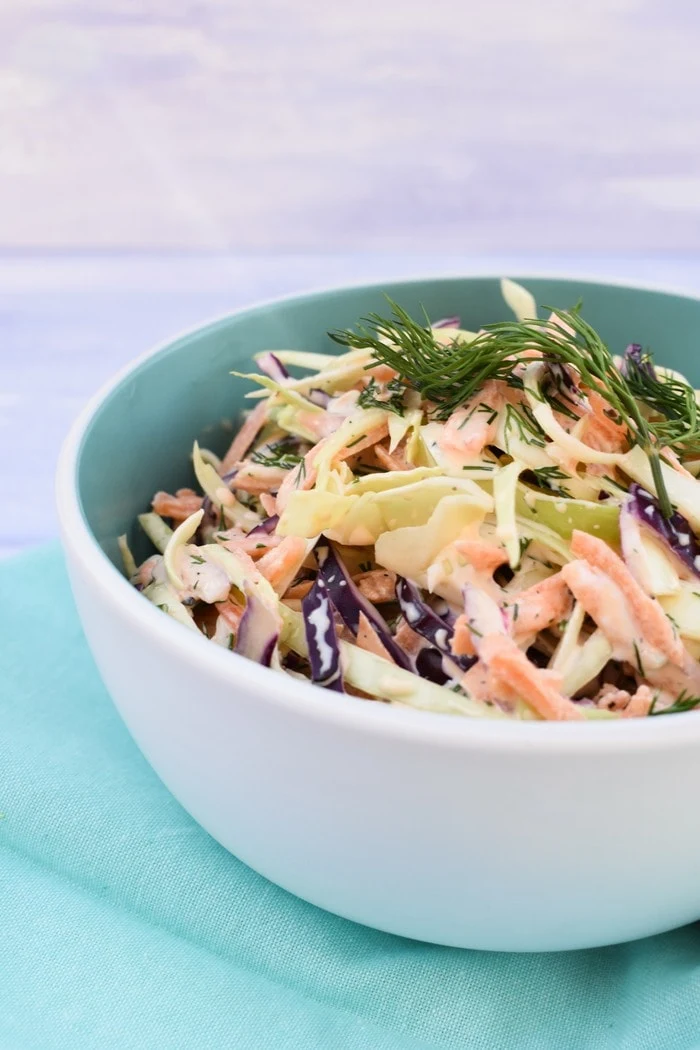 Close up of Vegan Coleslaw with Fresh Herbs in pale blue bowl on pale blue napkin