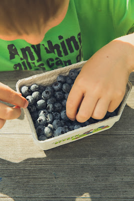 Child eating blueberries out of pint container