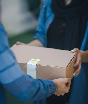 Mujer recibiendo un paquete de manos de un repartidor