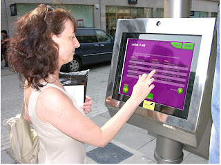 Picture shows a person using the touch screen: seeking local job vacancies. The screen is housed in a robust all weather frame. The touch screen is held beneath a special reinforced laminated glass membrane which is vandal hardened and easy to replace id seriously attacked. These things happen but the touch screen is safe beneath its protective replaceable barrier. Operating in Aberdeen since 2006. © PUBLIC DATAWEB