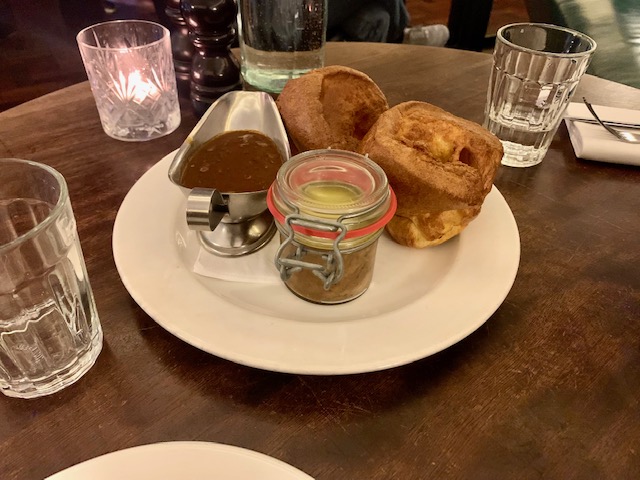 Plate containing potted meat, two Yorkshire puddings and a silver jug of gravy