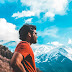 Man Standing on Mountain With Cloudy Background