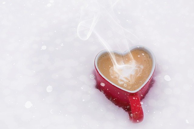 Heart shaped mug of hot coffee in the snow