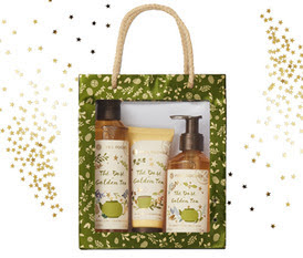 Imagem de uma caixa-saco de presente Yves Rocher de fundo verde-folha com motivos natalinos, contendo Banho duche Chá Dourado • 200 ml + Sabonete liquido mãos Chá Dourado • 190 ml + Creme hidratante mãos Chá Dourado • 75 ml 