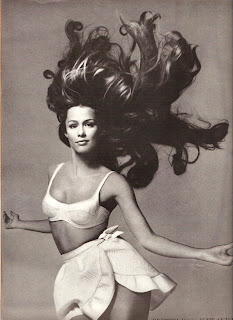 Vintage photo of Lauren Hutton jumping in a swimsuit with hair flying in the air.