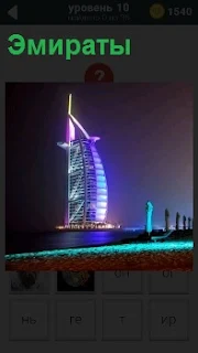 Освещенное здание в Эмиратах, которое стоит в середине водоема в виде паруса яхты