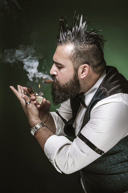 Handsome bear man suited with a mohawk lighting a cigar sideways