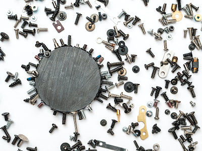 magnet on white background surrounded by screws and hardware