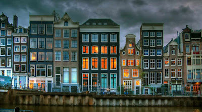 Ряд домов со светящимися окнами вдоль амстердамского канала