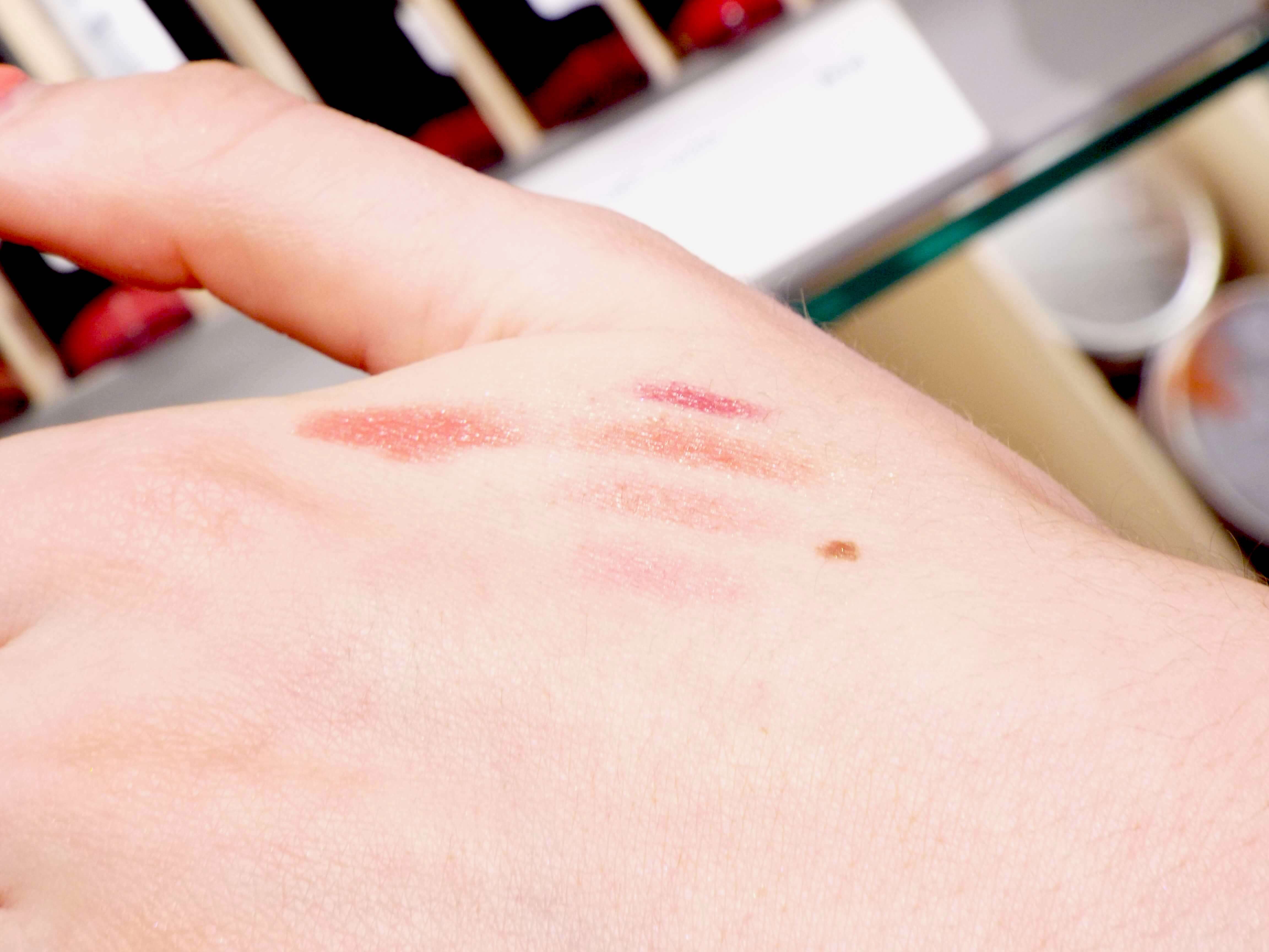 A selection of pink and nude lipsticks swatched on the back of Meg's hand.