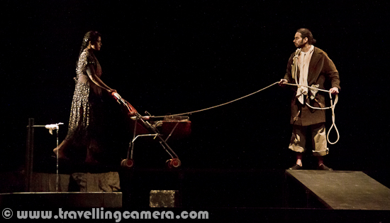 A theatre production co-produced by The Japan Foundation and Theatre Roots & Wings, `The Water Station` is a two-hour, wordless performance, written by an award-winning Japanese playwright Shogo Ohta, and directed by Sankar Venkateswaran, with an all-India cast selected by auditions across the country. Let's have a quick Photo Journey of 'The Water Station' play from 14th Bharat Rang Mahotsav 2012.Walking through a barren landscape, eighteen travelers stop by at a dripping waterfaucet. They drink, soak, meet, love, fight, weep, separate and in the end, leave, while a man living in a junk pile casually observes their actions from above. The play is about loneliness, the need for sustenance and the fragility of loveWithout any personal comments about the play, we would like to share a review of the same play available at http://www.dnaindia.com/analysis/comment_to-the-water-station-slowly-slowly_1629509 and can't comment on credibility of the reviewer in Indian TheatreCast of this play includes - Munmun Singh as girl, Ravindra Vijay S as first man, Sunil Bannur as second man with briefcase, Asha Ponikiewska as girl with umbrela, Anirudh Nair as husband, Kavita Srinivasan as wife, Yeshwanth Kuchabal as person sitting on scrap, Scherazade Kaikobad as Old lady, Smitha P as first daughter, Ishwari Bose-Bhattacharya as second daughter,Mandakini Goswami, Vinu Joseph, Sunitha, Siddhartha Mishra, GopalanThis play was showcases at Abhimanch Auditorium of National School of Drama and it was house full. Even then lot of folks were standing in the queues that they will get entry to stand around the corners. After few minutes of entry, whole auditorium was full and there was no space to walk and it was problematic for folks who wanted to leave early Sankar Venkateswaran's interpretation of Shogo Ohta's THE WATER STATION is an example of the kind of evocative avant-garde theatre that Indian audiences are not quite accustomed to. It features a procession of actors who traverse what may seem like a few meters on stage but with every moment stretched out lovingly (the play is performed in slow motion), each flicker of emotion acquires the quality of a full-blown tale, each gesture is drawn like a skein and woven into a texture of rich transfixing images that are frozen in time like a series of three-dimensional snapshots that capture illusions, and journeys and transformations without the loss of any small detail. Even as we pay rapt attention to the glacial pace of the actors' crossing, we are caught unaware sometimes by the uplifting cadences that waft our way despite the seeming lugubriousness of it all. It can be a difficult watch for a more restless audience, and some perseverance is required before it all pays off almost in transcendental fashion. (Crtesy - http://www.mumbaitheatreguide.com/dramas/reviews/30-the-water-station-english-play-review.aspThe only sound in the hall was dipping water from a tap on extreme left. Various characters were coming to this place to drink water as per their thirst level and moved on. Apart from water sound, there were sounds like click-click of cameras and some noises from back rows where some of the youngsters were not able to digest the idea of this play.  Many of the folks moved out of the auditorium, which may have various reasons - Like it was too late. Play started at 8:45 pm and it was 2 hrs long etcHere is another review written by someone who is not theatre critic, but a casual audience of Indian Theatre. He has appreciated the act and for more details, check out - http://acrazymindseye.wordpress.com/2011/05/13/thinking-aloud-about-water-stationCheck out following link to know more about the background of 'The Water Station' - http://www.cas.sc.edu/thea/2011/waterstation.htAnother experience of The Water Station can be found at http://inkpot.com/theatre/04reviews/04revwatestat.htmFor me as theatre lover and Photography enthusiast, this play was ok and not very interesting. After watching this play, first time I realized that probably I like humorous plays and plays which at least has strong methods of expressions. This play was too slow for me and low lighting also challenged to take appropriate photographs. This is first time, I had to click photographs at 6400 ISO... But at the same time, many folks in the theatre were enjoying it a lot !!This play was extremely slow and even upto an extent that a girl took approximately 10 minutes to walk 6 meters of distance. Since most of the details about the play is already available on web, I would stop here and keep watching the photographs to complete the Photo Journey from The Water Station....With these, Photo Journey of The Water Station from 14 Bharat Rang Mahotsav 2012 end here... Keep watching this space for more Photo Journeys from Chandalika, Vyomkesh etc..