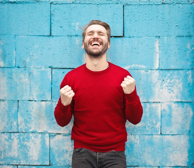 Man wearing a red long sleeves, is showing the emotion of happiness