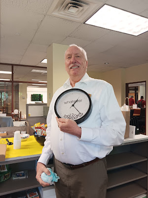 David Stanley holding a clock that reads "whatever" across the face with all of the numbers in a heap at the bottom