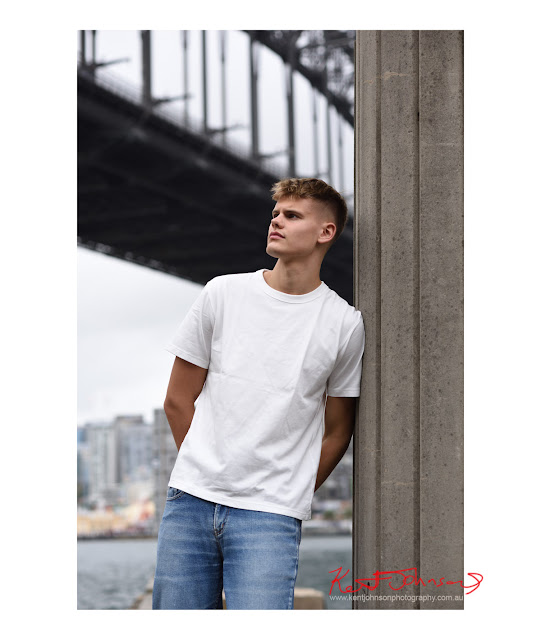 Linus, mid-shot in colour with arms behind his back, w/Sydney Harbour Bridge in background