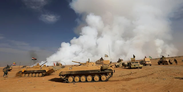 Image Attribute: Iraqi army gather after the liberation of a village from Islamic State militants, south of Mosul, during an operation to attack Islamic State militants in Mosul, Iraq, October 21, 2016, as toxic smoke is seen over the area after Islamic State militants set fire to a sulphur factory. REUTERS/Thaier Al-Sudan