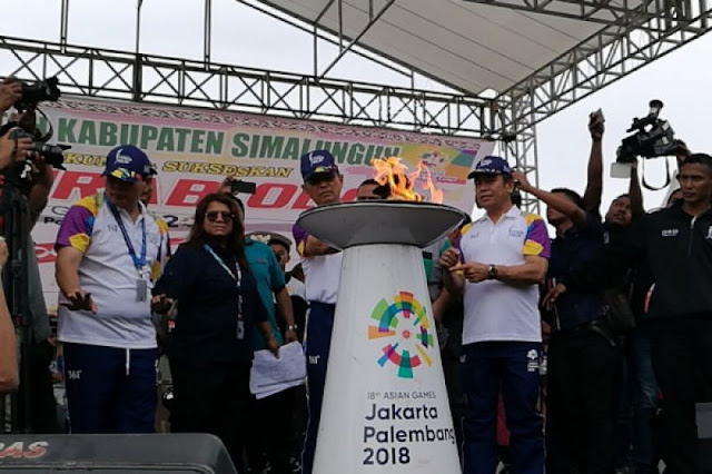 Bupati Simalungun JR Saragih menyulutkan api Asian Games 2018 dari obor ke mini cauldron di Pantai Bebas, Danau Toba, Sumatera Utara